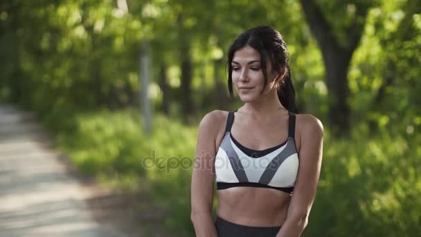 Porträtt av en vacker ung flicka idrottare. modell i sportkläder poserar för kameran och ler. — Stockvideo