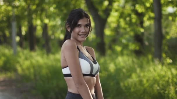 Joven linda mujer joven en ropa deportiva posando y sonriendo a la cámara. la chica atleta difundir la belleza y la salud — Vídeos de Stock