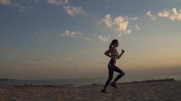 Chica de 20 años corriendo en la arena en la playa al atardecer. Correr al aire libre . — Vídeos de Stock
