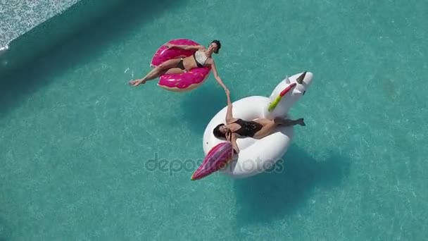 Aérea - chicas sexy tomando el sol y nadando en la piscina. Chicas jóvenes y atractivas descansan en un día soleado. Tiro con quadrocopter — Vídeo de stock