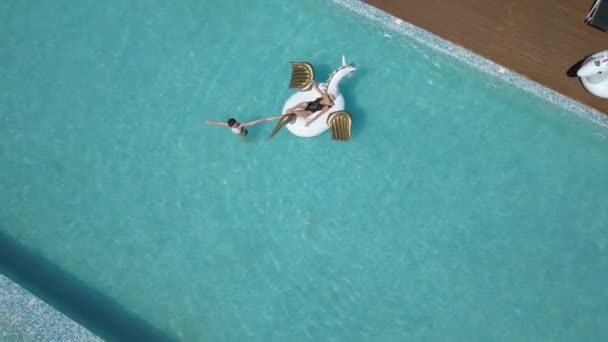 Aérea: joven mujer sexy en bikini flotando en un colchón de aire en la piscina. chicas atractivas tomando el sol. Tiro con quadrocopter — Vídeos de Stock