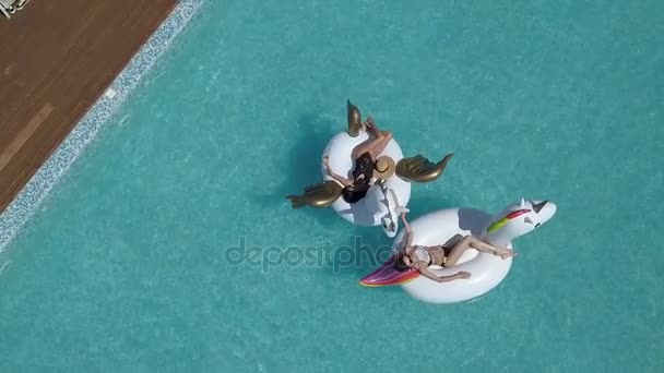 Antenn - flickor dopp i poolen. två vänner liggande på uppblåsbara madrasser och sola. semester till havs på en varm sommardag. Skytte med quadrocopter — Stockvideo
