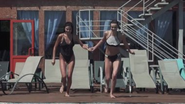 neşeli kız çalıştıran havuza atlamak ve su damla yükseltmek. ağır çekim