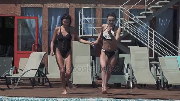 실행 하는 쾌활 한 여자 친구는 수영장으로 점프 하 고 물 방울을 인상. 슬로우 모션 — 비디오