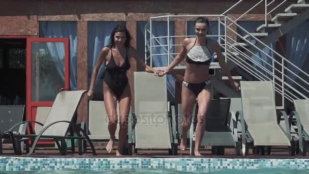 Веселі подружки стрибають у басейн і піднімають краплю води. повільний рух — стокове відео