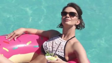 Bir şişme şişme havuzu güneşlenme bikinili bir kızın portresi. Bir kokteyl içme ve sıcak güneşli bir gün zevk güzel genç kadın