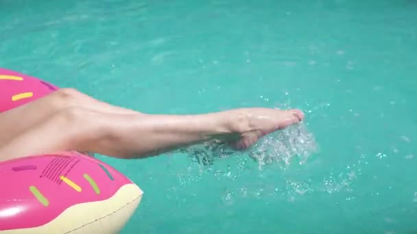 Close-up portret van een jonge vrouw in een bikini. Mooi meisje in zonnebril drinkt een frisdrank liggend op een opblaasbare matras donut in een buitenzwembad — Stockvideo