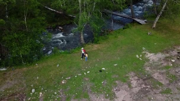 空中。家族は、山の中のストリームの横について説明します。子供たちにスポーツのママは、ハイキングを行っています。アルタイ、シベリア。航空カメラで撮影 — ストック動画