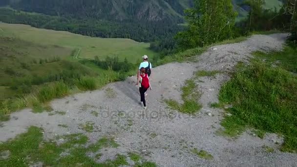 Légi. férfi és a nő a szélén egy sziklán a hegyekben. a turistákat a nyaralás egy gyönyörű hely a természetben. családi utazó. Altáj, Siberia. Légi kamera felvétel — Stock videók