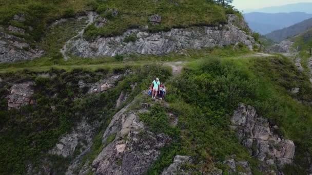 Antény. šťastná rodina šli kempování. turisté na dovolené. rodiče s dětmi obdivovat překrásný výhled, sedící vedle útesu v horách... Altaj, Sibiř. Letecká kamera natáčela — Stock video