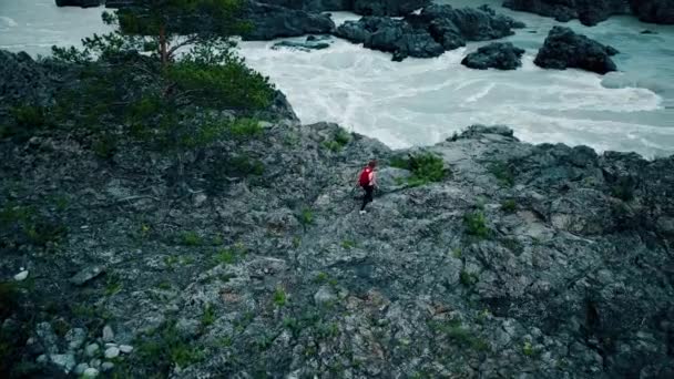 Antenn. kvinna turist med ryggsäck är på klipporna för att en fjällbäck. flicka traveler har promenaden. Altai, Sibirien. Flygande kameran skott — Stockvideo