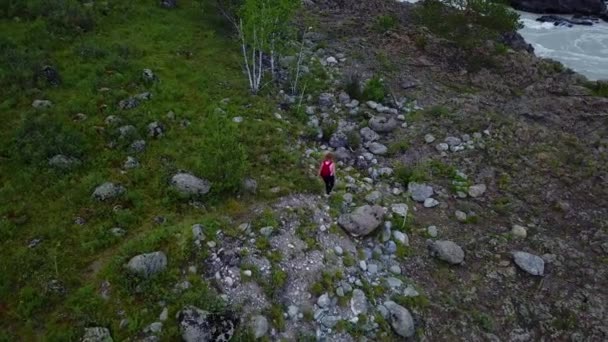 Antenowe. turystyczna kobieta z plecaka jest na skałach do górskiego strumienia. podróżnik dziewczyna cieszy się spacerem. Ałtaj, Siberia. Aerial strzał kamera — Wideo stockowe