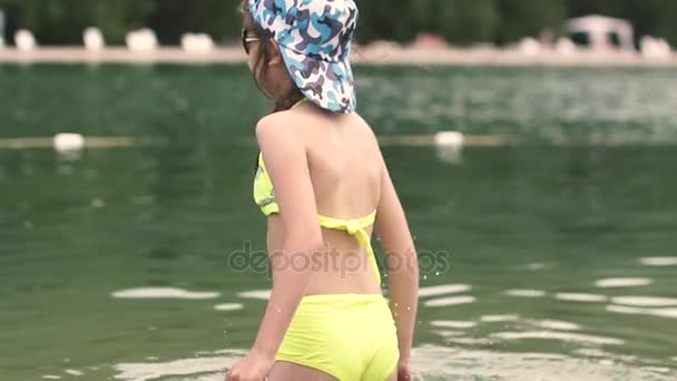 Çocuk eğleniyor ve gölde yüzmeye. Su kenarındaki dinlenme zevk küçük kız. Ağır çekim — Stok video