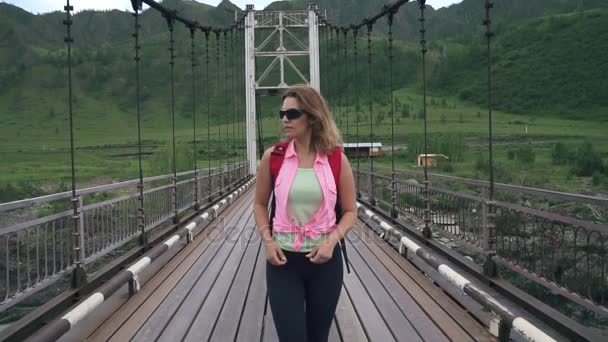 Chica turista con una mochila corre hacia la aventura. Una joven viajera corre por el puente. cámara lenta — Vídeo de stock