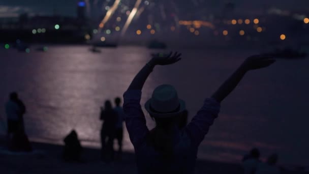 Sziluettjét, egy lány, a háttérben a tűzijáték. a nő boldogan emeli a kezét, és a szórakozás a nyaralás — Stock videók