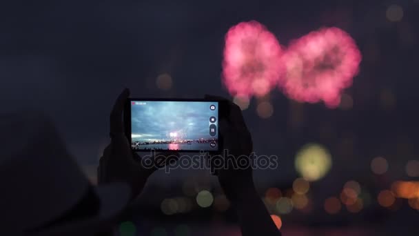 Mujer dispara fuegos artificiales en un teléfono móvil. manos de la mujer que toma la foto a los fuegos artificiales con el teléfono inteligente — Vídeos de Stock