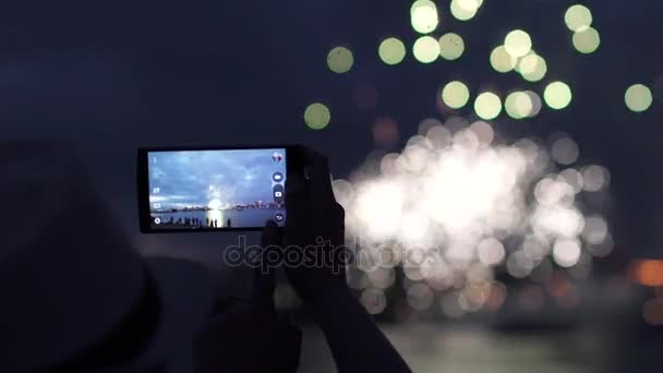 Mujer dispara fuegos artificiales en un teléfono móvil. manos de la mujer que toma la foto a los fuegos artificiales con el teléfono inteligente — Vídeos de Stock