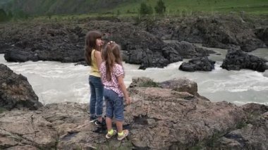 küçük kız yakınlarında bir dağ nehir taşları üzerinde ve çarpıcı manzarasının tadını çıkarın. Kızlar Gezgin elele. Çocuk macera arayışı içinde seyahat