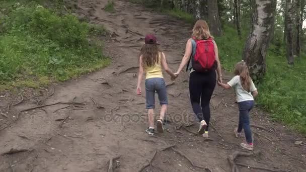 Matki z córkami wyrusza w podróż. Rodzina turystów pod górę na leśnym szlaku — Wideo stockowe