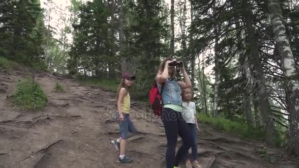 母亲和儿童透过望远镜。在森林里的家庭旅行。女人用背包显示儿童自然之美 — 图库视频影像