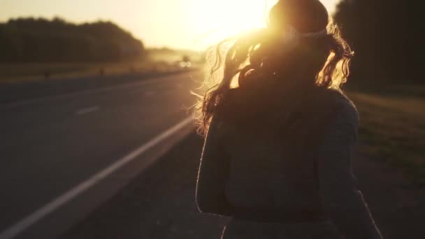 Chica con la ropa hippie corre en el camino al amanecer. La chica está de camino al amanecer. joven atractiva mujer en ropa hippie sonriendo y mirando a la cámara. cámara lenta — Vídeo de stock