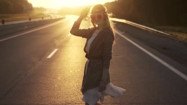 Menina vestida em estilo hippie está na estrada. retrato de jovem mulher em óculos de sol. câmara lenta — Vídeo de Stock