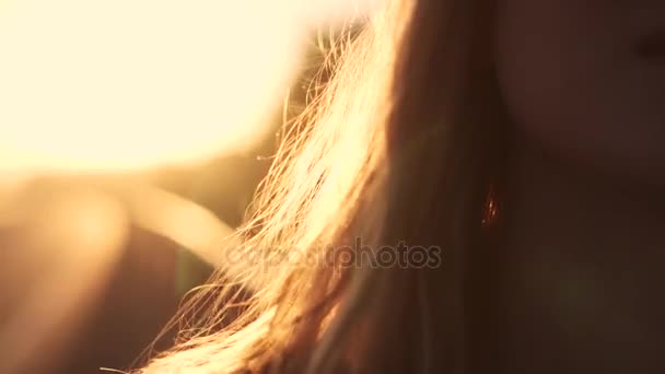 Closeup πορτρέτο του ένα όμορφο κορίτσι στην αυγή. μια νεαρή γυναίκα αγγίζει τα μαλλιά. η ήλιοι ακτίνες και αντανάκλαση — Αρχείο Βίντεο