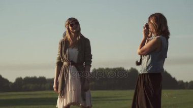 Kız hippi kız arkadaşı fotoğraflarını bir film kamerası. iki genç kadın şafakta fotoğraflandı.