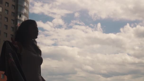 Silhouette of beautiful girl on a background of sky, clouds and modern buildings. slow motion — Stock Video