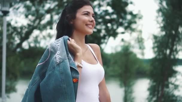 Carefree girl walks leisurely along the summer park. Portrait of a beautiful girl close-up on a background of green trees. slow motion — Stock Video