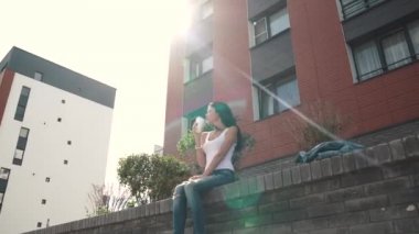 Çekici seksi kız sokakta otururken kahve içecekler