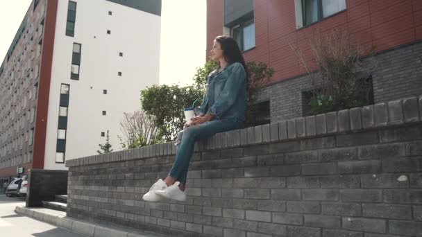 Dívka venku pití kávy, zatímco sedí na parapetu — Stock video