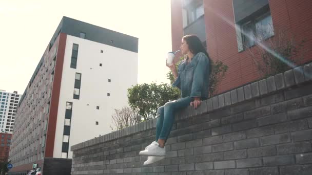 Mädchen trinkt Kaffee im Freien, sitzt auf der Brüstung — Stockvideo