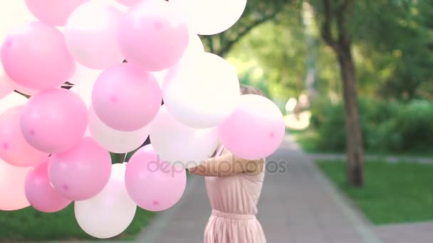 Mujer joven feliz gira sosteniendo globos de aire. Movimiento lento — Vídeos de Stock