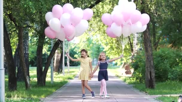 Portret dwóch dziewczynek z balonami w ich rękach. szczęśliwe dzieci beztroski w lato Park — Wideo stockowe