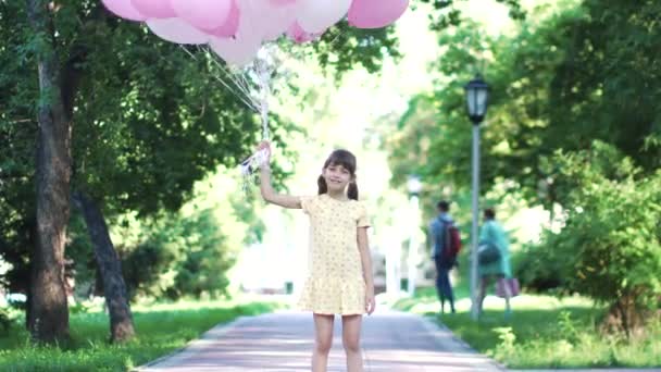 Портрет маленької дівчинки з повітряними кулями в руках. безтурботний і щасливий дитина на відкритому повітрі — стокове відео
