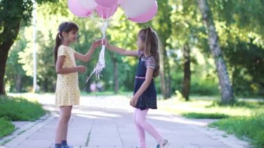 küçük bir kız balon buketi kız arkadaşına verir. iki küçük kız kardeş yaz Park