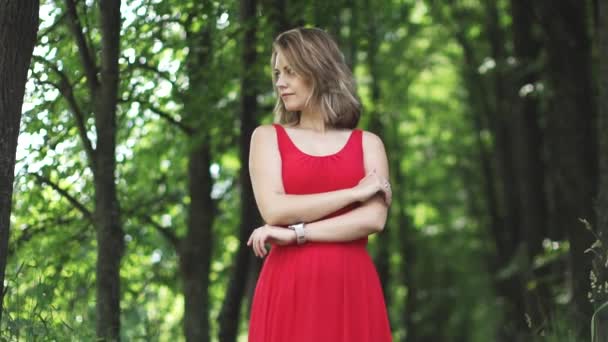 Portrait de jeune femme en robe rouge sur fond bokeh vert. au ralenti — Video