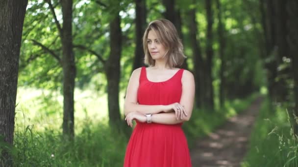 Porträtt av ung kvinna i röd klänning på gröna bokeh bakgrund. slowmotion — Stockvideo