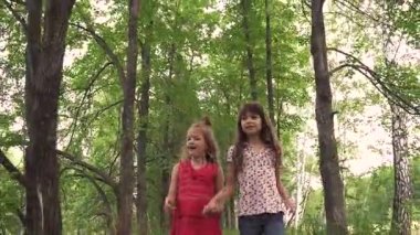 iki küçük kız el ele tutuşup yeşil sokakta yürümek. çocuklar açık havada yürümek. iki küçük kız kardeş