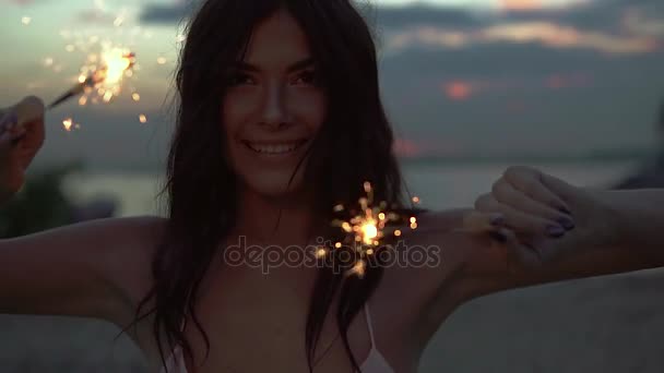 ベンガル ライトで美しい少女のクローズ アップの肖像画。笑顔でカメラを見て海辺で若い女性の踊り。スローモーション — ストック動画