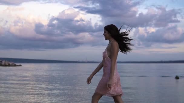 Mädchen im Cocktailkleid geht unbeschwert am Strand bei Sonnenuntergang spazieren — Stockvideo