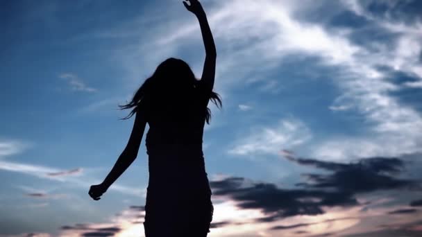 Silhueta de uma menina dançando em um por do sol de fundo. menina bonita dançando e se divertindo ao ar livre — Vídeo de Stock