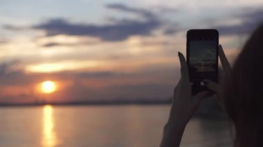 Kız cep telefonu kamera günbatımı fotoğraflarını çeker