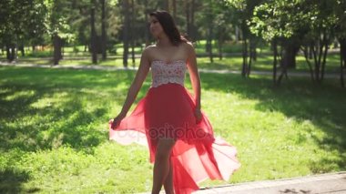 güzel kızla yaz Park topuklu kırmızı elbise ve ayakkabı. rüzgarda çırpınan elbise. ağır çekim