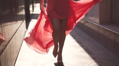 batan güneşin içinde sokakta yürürken Kırmızı elbiseli kız. ağır çekim