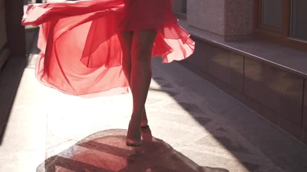 dívka v červených šatech na ulici v zapadajícím slunci. Zpomalený pohyb