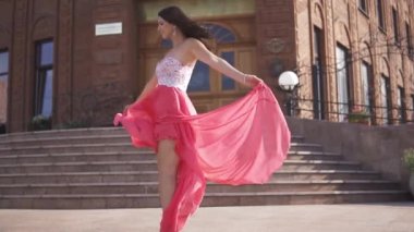 Akşam elbiseli çekici kız eğlenceli ve başım dönüyor sokakta yaşıyor. Rüzgarda çırpınan bez.