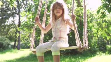 Yaz Park'ta bir salıncak üzerinde sallanan küçük kız. ağaca bağlı ipler üzerine salıncak. mutlu bir çocukluk. ağır çekim