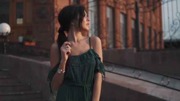 Portrét krásné dívky s večerní líčení a účes. Roztomilá brunetka pózuje pro kamery při západu slunce na pozadí města — Stock video
